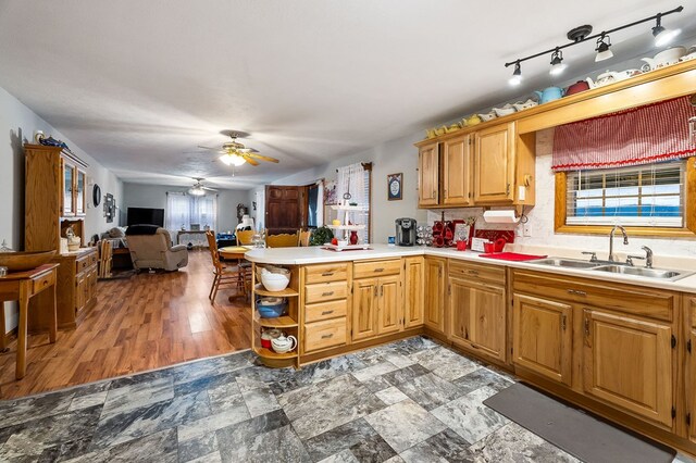 kitchen with ceiling fan, a peninsula, a sink, open floor plan, and light countertops