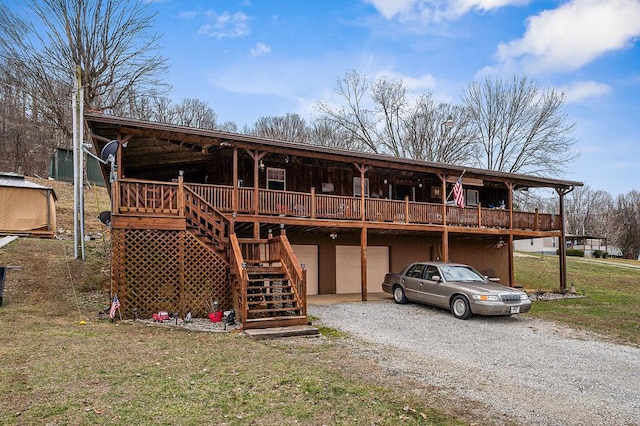 back of property with a lawn, an attached garage, driveway, a wooden deck, and stairs