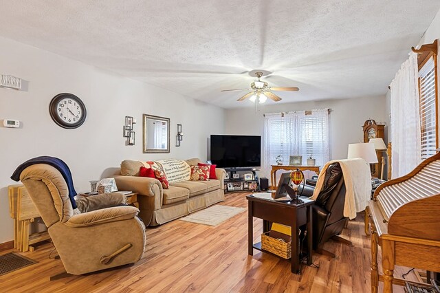 living room featuring a textured ceiling, a ceiling fan, and light wood-style floors