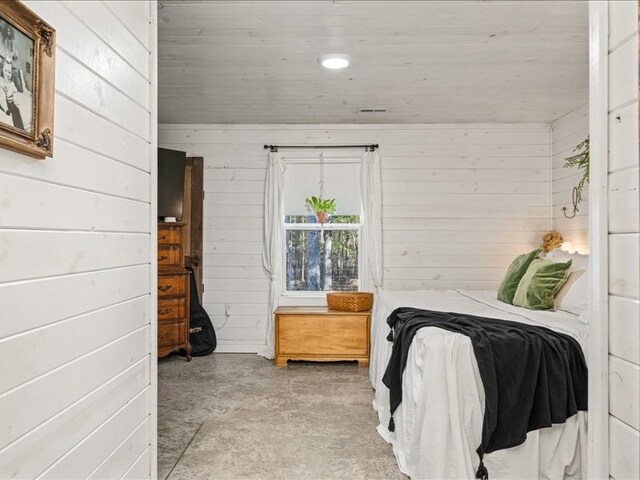 bedroom featuring wood walls and concrete floors