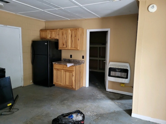 kitchen with freestanding refrigerator, unfinished concrete flooring, concrete block wall, and heating unit