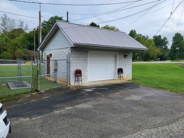 detached garage featuring aphalt driveway and fence