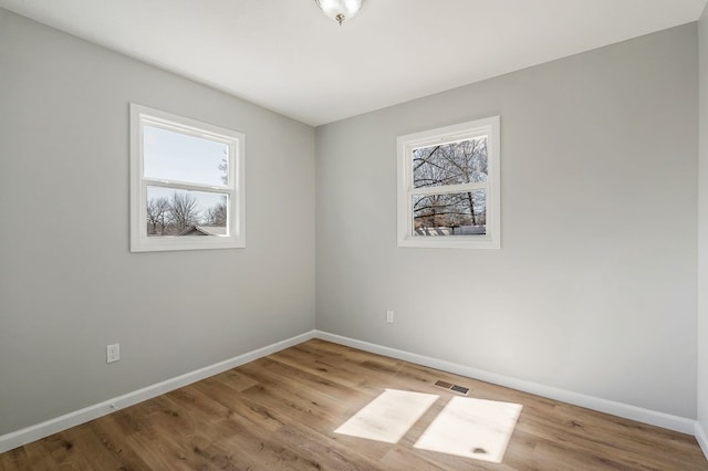 unfurnished room featuring visible vents, baseboards, and wood finished floors