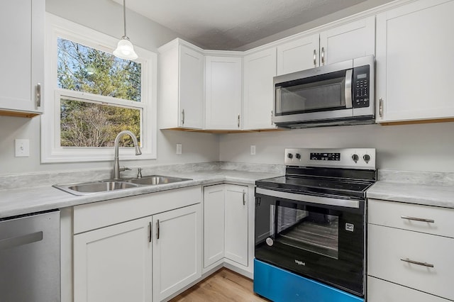 kitchen featuring a sink, hanging light fixtures, light countertops, white cabinets, and appliances with stainless steel finishes