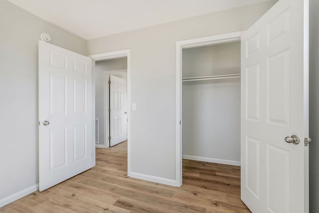 unfurnished bedroom with light wood-style floors, baseboards, and a closet