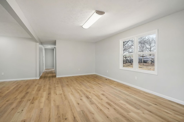 empty room with light wood-type flooring and baseboards