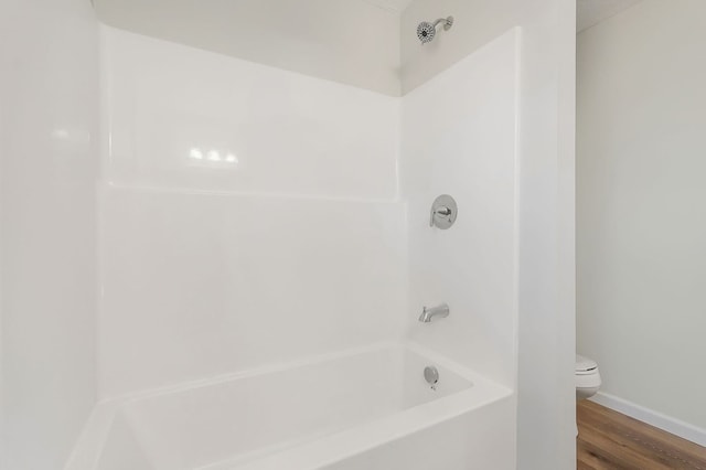 bathroom with toilet, shower / washtub combination, and wood finished floors