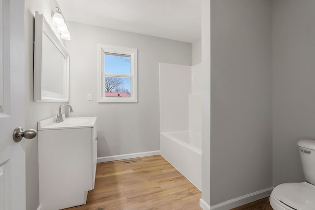 bathroom featuring toilet, vanity, baseboards, and wood finished floors