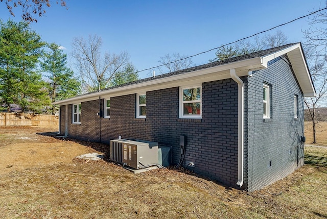 view of side of property with brick siding, crawl space, cooling unit, and fence