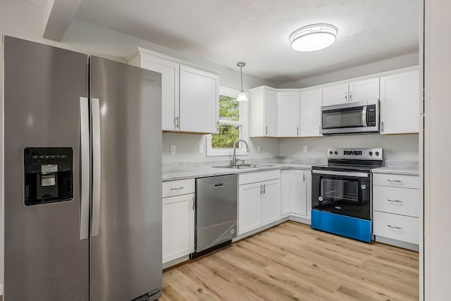 kitchen with a sink, stainless steel appliances, white cabinets, and light countertops