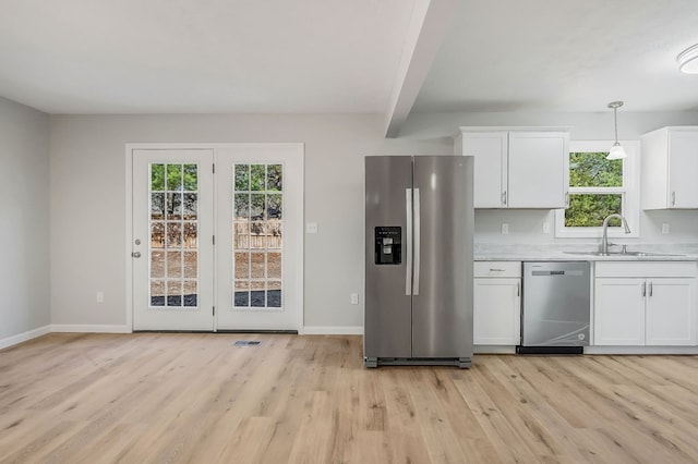 kitchen with light countertops, appliances with stainless steel finishes, light wood-style floors, white cabinets, and a sink