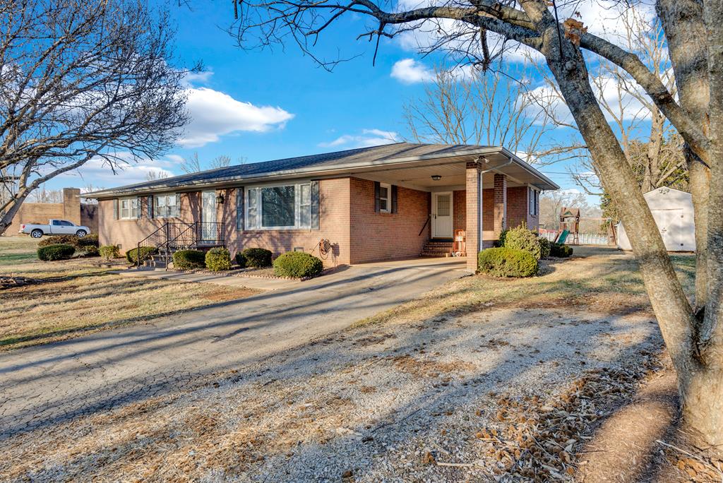 single story home featuring entry steps, driveway, brick siding, and an attached carport