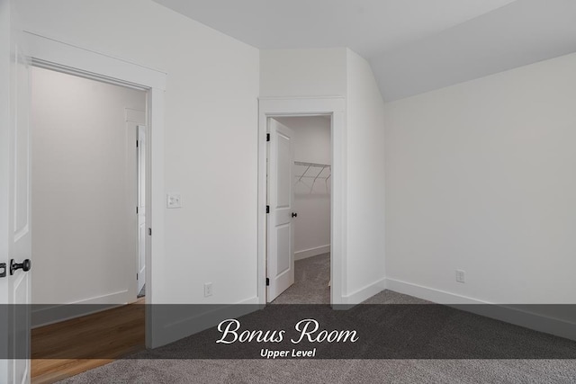 unfurnished bedroom with a spacious closet, carpet, and baseboards