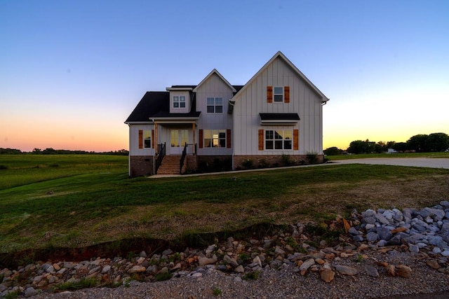 view of front of property with covered porch, a lawn, and board and batten siding