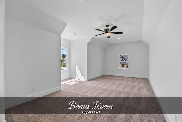 additional living space with light carpet, vaulted ceiling, and baseboards