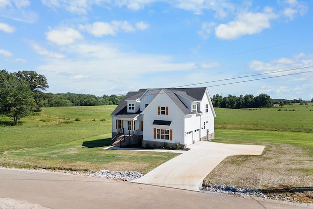 modern farmhouse style home with a front yard, a rural view, driveway, and an attached garage