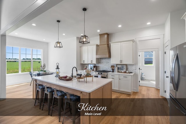 kitchen featuring appliances with stainless steel finishes, light countertops, white cabinets, and an island with sink