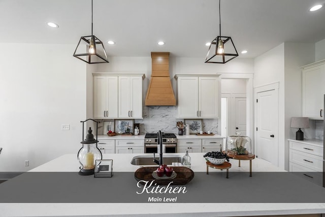 kitchen with light countertops, custom exhaust hood, a center island with sink, and pendant lighting