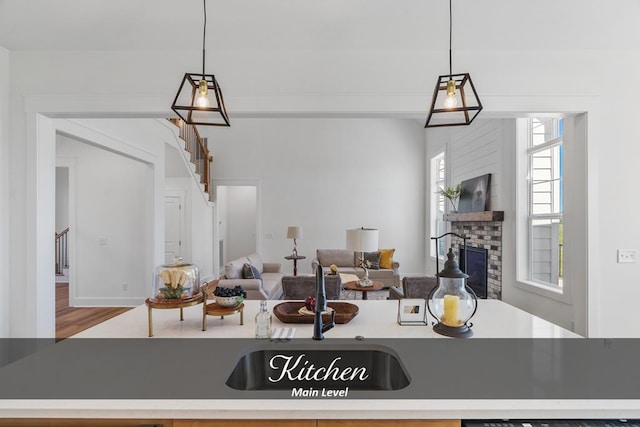 kitchen featuring a fireplace, wood finished floors, open floor plan, hanging light fixtures, and light countertops