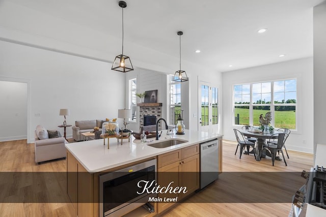 kitchen featuring a sink, open floor plan, light countertops, stainless steel dishwasher, and an island with sink