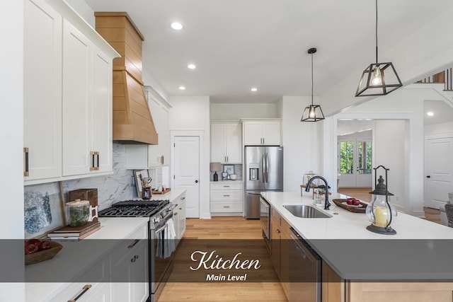 kitchen with a sink, white cabinets, light countertops, appliances with stainless steel finishes, and an island with sink