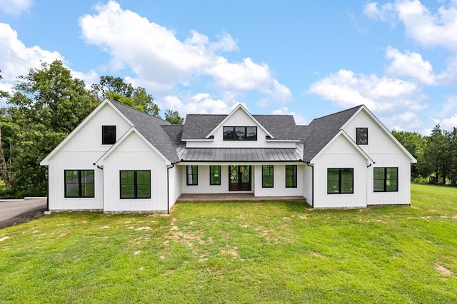 rear view of property featuring metal roof, a shingled roof, a lawn, board and batten siding, and a standing seam roof