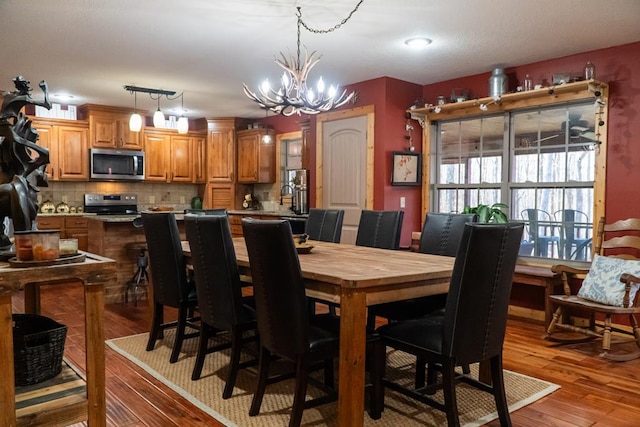 dining area with light wood-type flooring and a notable chandelier