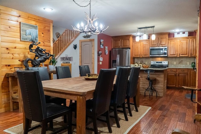 dining room featuring stairway, dark wood finished floors, and a notable chandelier