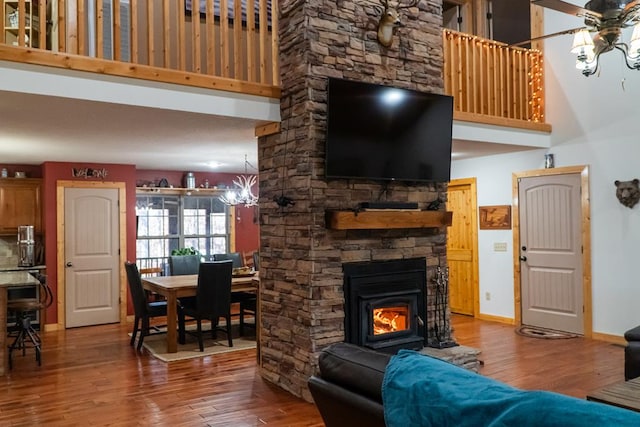 living room featuring a high ceiling, baseboards, wood finished floors, and ceiling fan with notable chandelier