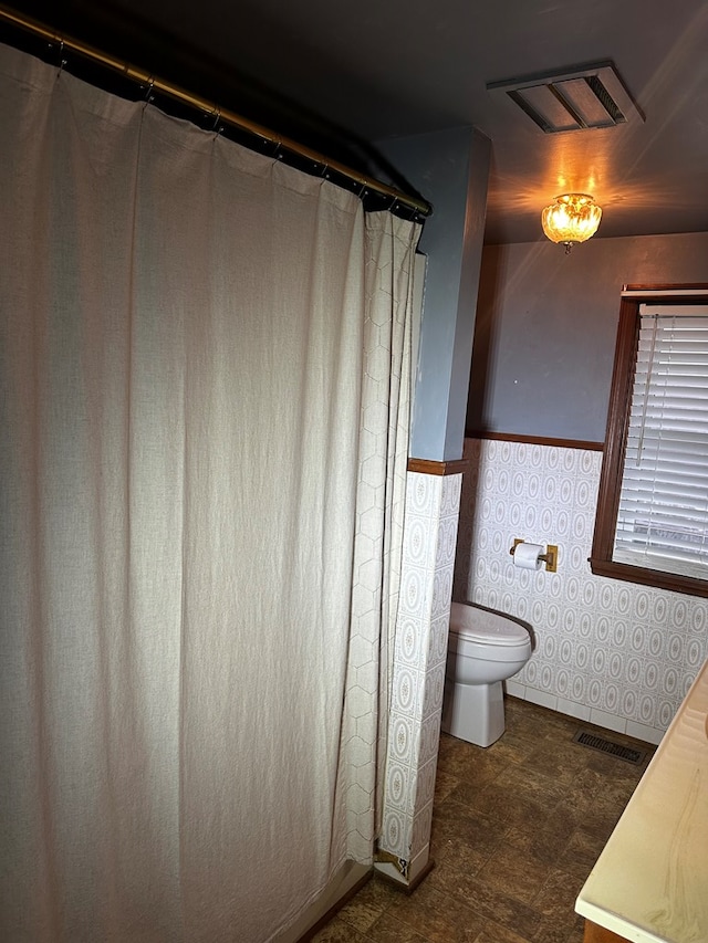 full bathroom featuring toilet, wainscoting, vanity, and visible vents