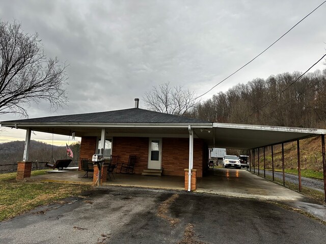 view of parking / parking lot featuring aphalt driveway, an attached carport, and entry steps