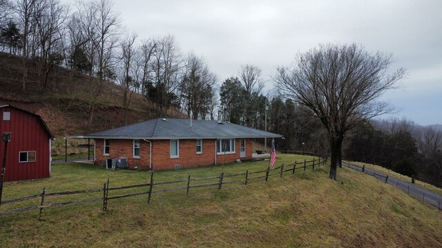 view of yard with a rural view, cooling unit, an outdoor structure, a barn, and fence