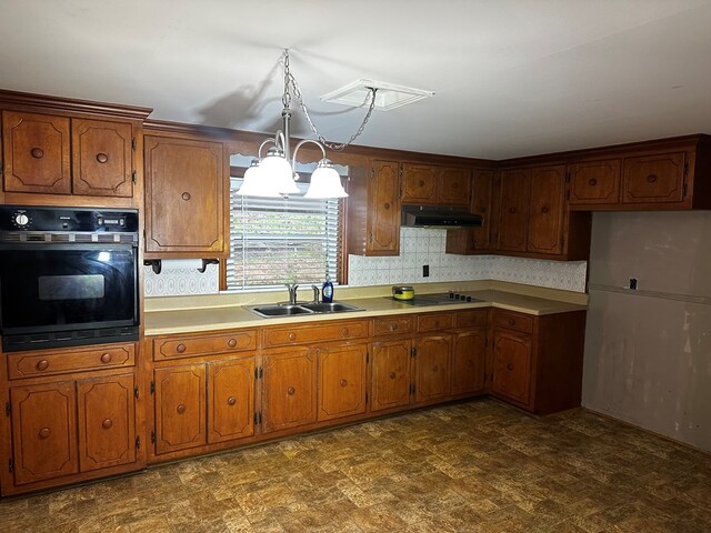 kitchen featuring brown cabinets, under cabinet range hood, light countertops, black appliances, and a sink