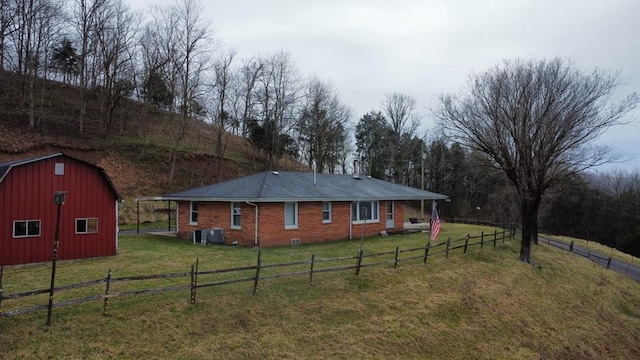 exterior space featuring a barn, a rural view, an outbuilding, fence, and central air condition unit