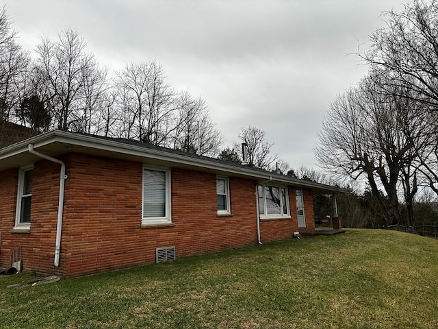 view of home's exterior featuring brick siding and a lawn