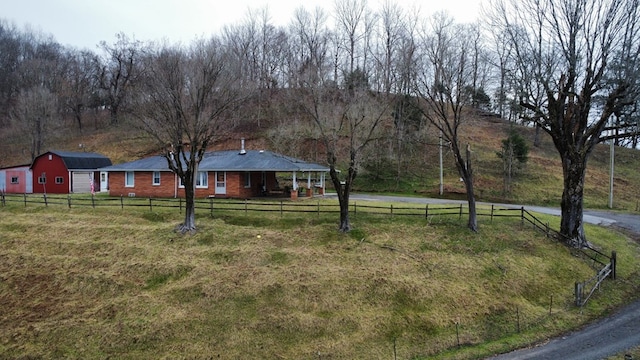 view of yard with a barn, a rural view, an outdoor structure, and fence