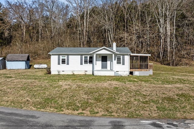 view of front of house with a sunroom, an outbuilding, crawl space, a shed, and a front lawn