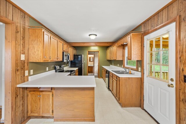 kitchen featuring stainless steel appliances, a peninsula, a sink, light countertops, and light floors