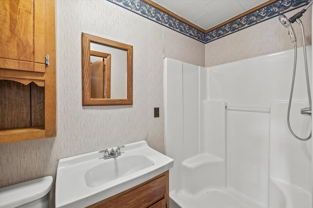 full bathroom with a shower, vanity, toilet, and wallpapered walls