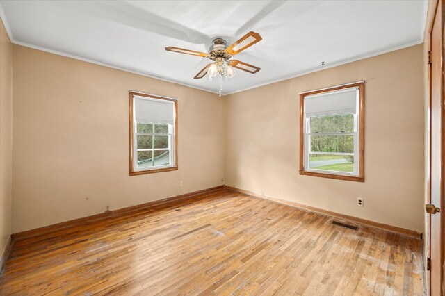 spare room with visible vents, baseboards, ceiling fan, ornamental molding, and light wood-type flooring