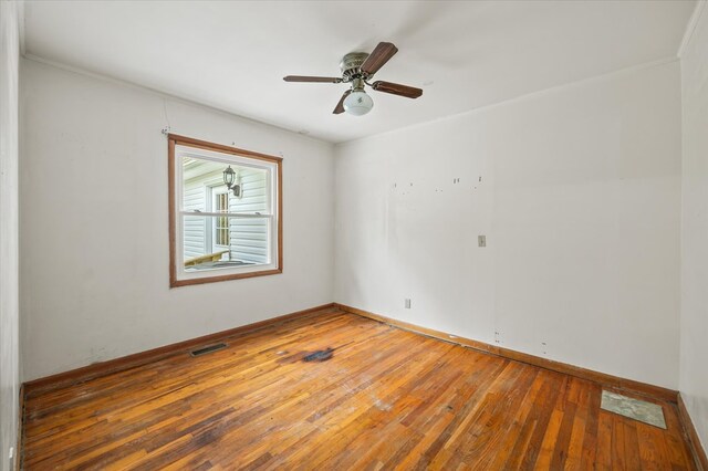 spare room with visible vents, ceiling fan, hardwood / wood-style flooring, and baseboards