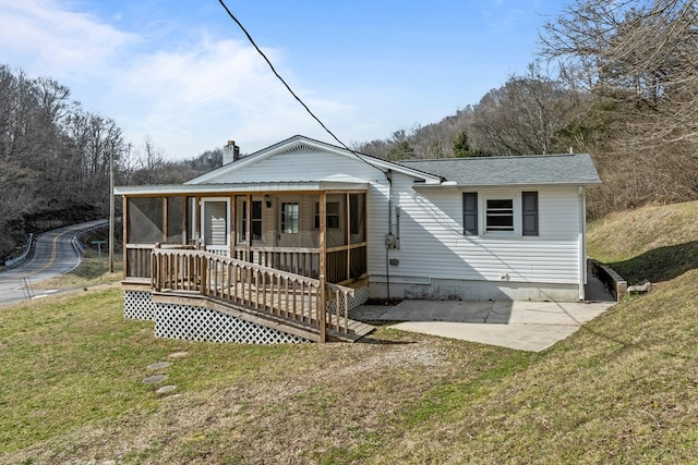 rear view of property featuring a sunroom, a lawn, and roof with shingles