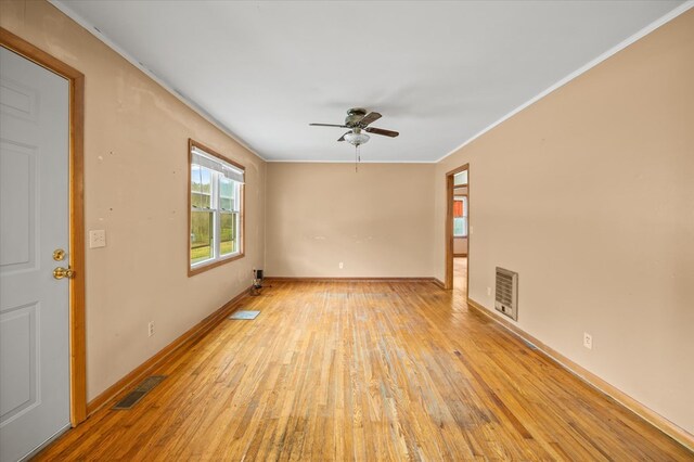 empty room featuring visible vents, baseboards, light wood-style flooring, ceiling fan, and crown molding