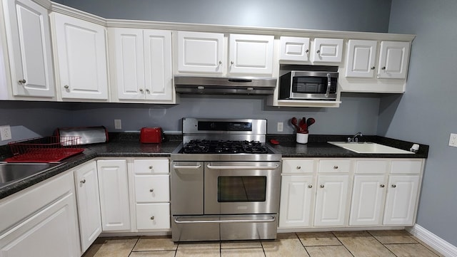 kitchen with under cabinet range hood, white cabinetry, stainless steel appliances, and a sink