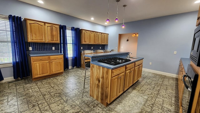 kitchen with dark countertops, a kitchen island, brown cabinetry, and decorative light fixtures