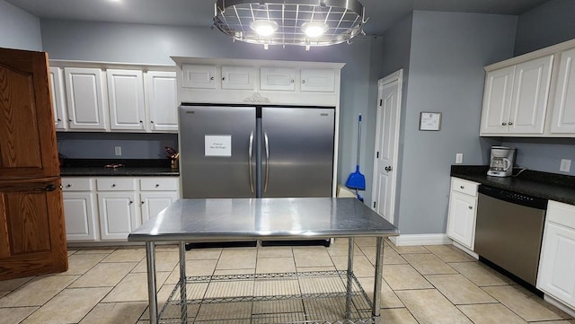 kitchen with light tile patterned floors, stainless steel appliances, baseboards, white cabinets, and dark countertops