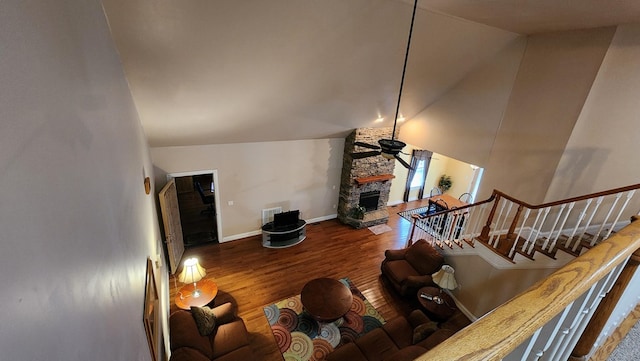 living area with ceiling fan, a stone fireplace, wood finished floors, baseboards, and stairway