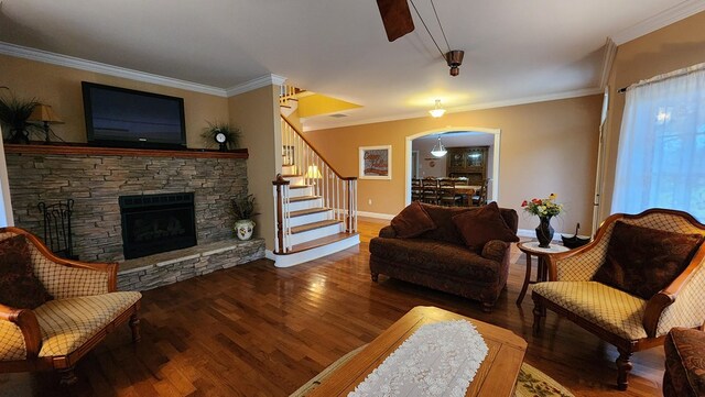 living area featuring arched walkways, stairway, dark wood-style flooring, crown molding, and a fireplace