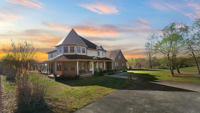 view of front of home with aphalt driveway, a front lawn, and a porch