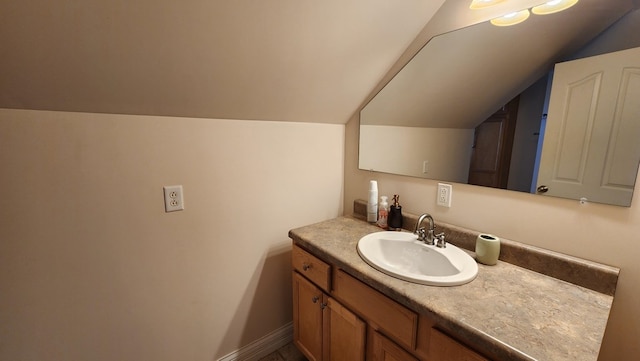 bathroom with baseboards, vaulted ceiling, and vanity